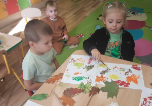 Ola i Mikołaj podczas tworzenia kompozycji ze stempli pomalowanych liśći.