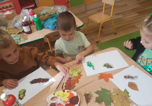 Ola, Filip i Mikołaj malują liście farbami.