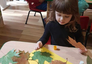 Helenka tworzy jesienną kompozycję z liści.