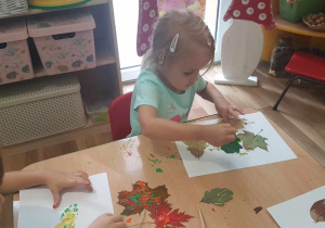 Lidia maluje liście farbami.