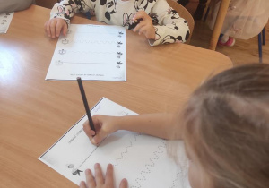 Dzieci wykonują ćwiczenia grafomotoryczne.