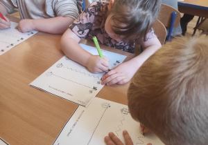 Dzieci wykonują ćwiczenia grafomotoryczne.