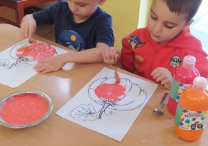 Dzieci dekorują sylwetę dyni masą "rosnących farb"