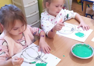 Dzieci dekorują sylwetę dyni masą "rosnących farb"