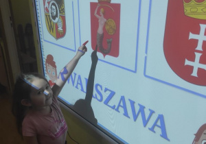 Ada wskazuje herb Warszawy.