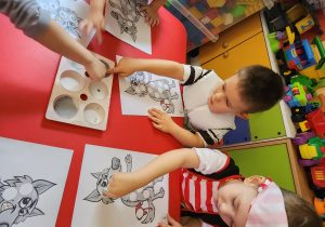 Jaś L, Franio i Oliwier malują farbami za pomocą paluszków.