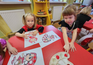 Alicja i Blanka malują farbami za pomocą paluszków.