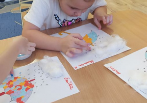 Dzieci robią kropelki deszczu maczając palec w farbie