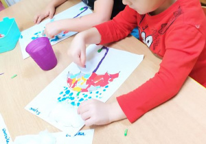 Dzieci robią kropelki deszczu paluszkiem umoczonym w farbie