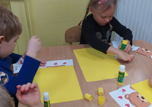 Dzieci układają i przyklejają misiowe puzzle