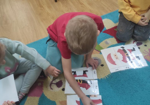 Dzieci układają puzzle z Mikołajem.