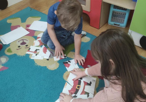 Dzieci układają puzzle z Mikołajem.