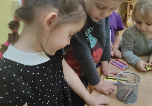 Dzieci układają taką samą liczbę kredek jak prezentów.