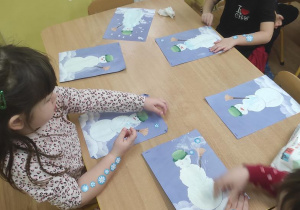 Dzieci malują bałwanka i naklejają śnieżynki.
