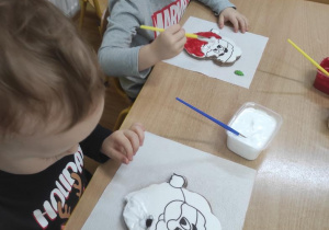 Dzieci malują lukrem Mikołaja z piernika.