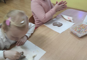 Dzieci malują lukrem pierniczki a następnie je ozdabiają.