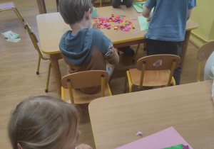 Dzieci formują bombki z bibuły i naklejają na choince.