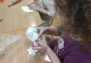 Dzieci wałkują masę porcelanową a następnie wykrawają kształty.