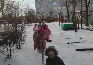 Dzieci na spacerze w ogrodzie przedszkolnym.
