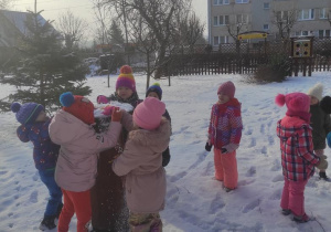 Dzieci oglądają zaśnieżony zegar słoneczny.