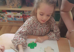 Zosia maluje breloczki zieloną farbą.