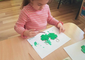 Matylda maluje breloczki zieloną farbą.