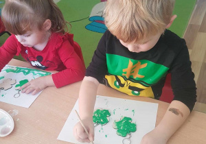 Michał maluje breloczki zieloną farbą.