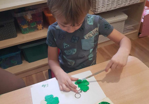 Filip maluje breloczki zieloną farbą.