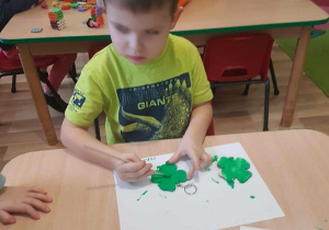 Mikołaj maluje breloczki zieloną farbą.