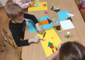 Dzieci wymyślają i układają ufoludka z figur geometrycznych.