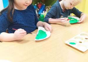 Marysia i Zosia wykonują pracę plastyczną - dinozaura z papierowego talerzyka