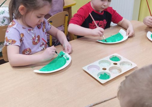 Dzieci wykonują pracę plastyczną - dinozaura z papierowego talerzyka
