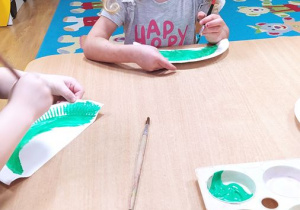 Nikola wykonuje pracę plastyczną - dinozaura z papierowego talerzyka