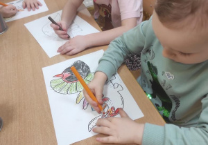 Dzieci kolorują dinozaura.