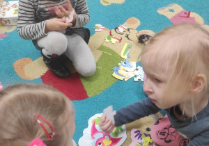 Dzieci układają puzzle z dinozaurami.