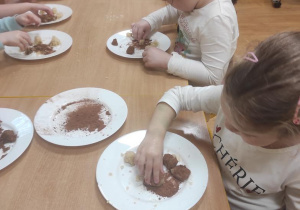 Dzieci obtaczają kulki marcepanowe w kakao.