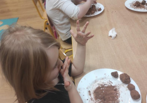 Dzieci obtaczają kulki marcepanowe w kakao.