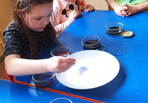 Dzieci wykonują eksperyment "Tęcza" z użyciem barwników i mleka
