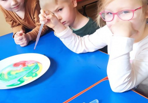 Dzieci wykonują eksperyment "Tęcza" z użyciem barwników i mleka
