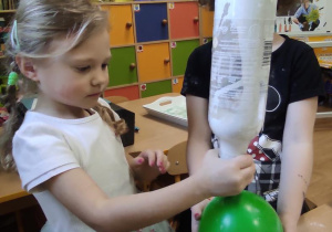 Nikola przesypuje mąkę z butelki do balonika. Pomaga jej Lila.