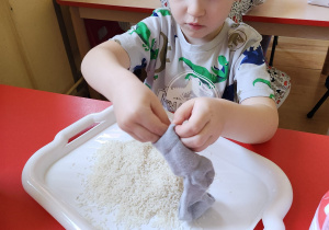 Olek napełnia skarpetę ryżem.