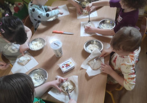 Dzieci przygotowują kanapki z twarożkiem.