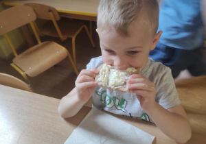 Filip zjada wykonaną kanapkę z twarożkiem.