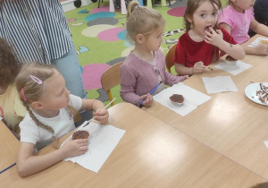 Dzieci ozdabiają babeczki płynna czekoladą.