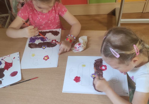 Dzieci malują farbami plakatowymi wybrane rysunki babeczek.