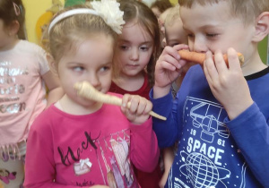 Dzieci oglądają i wąchają warzywa.