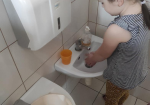 Marysia wykonuje doświadczenie - ile wody zużywa podczas mycia rąk.