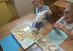 Maks wsypuje popcorn na tacę.