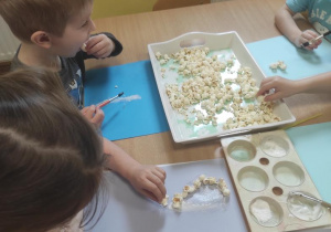 Dzieci przyklejają popcorn.