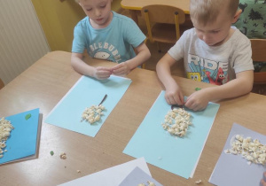 Dzieci przyklejają popcorn i lepią łodygę i liście.